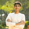 Portrait of happy teenage boy with arms crossed at park